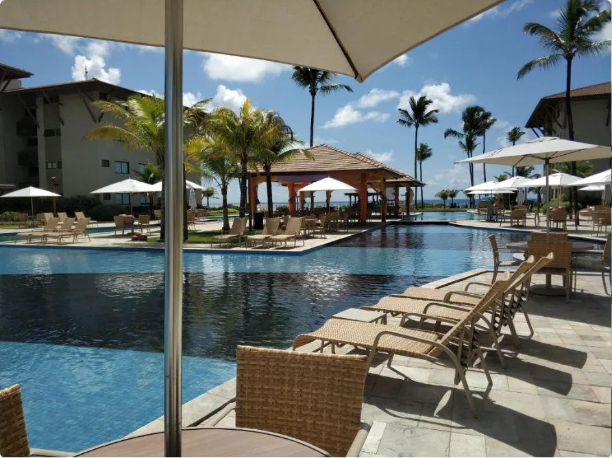 Piscina com quiosque e espreguiçadeiras no condomínio Polinésia Resort